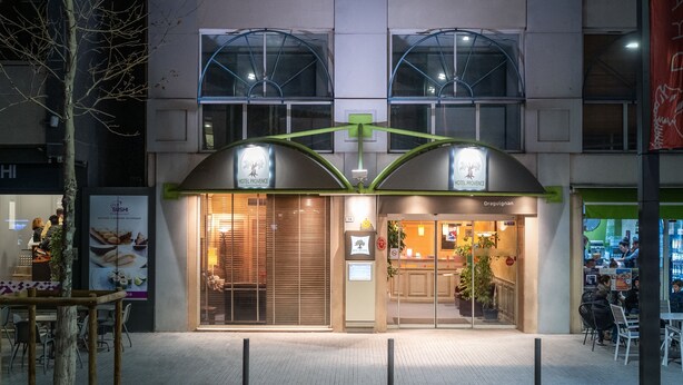 Entrada de hotel con un toldo verde, letrero de restaurante de sushi y un letrero que dice 'Dragouignan'.