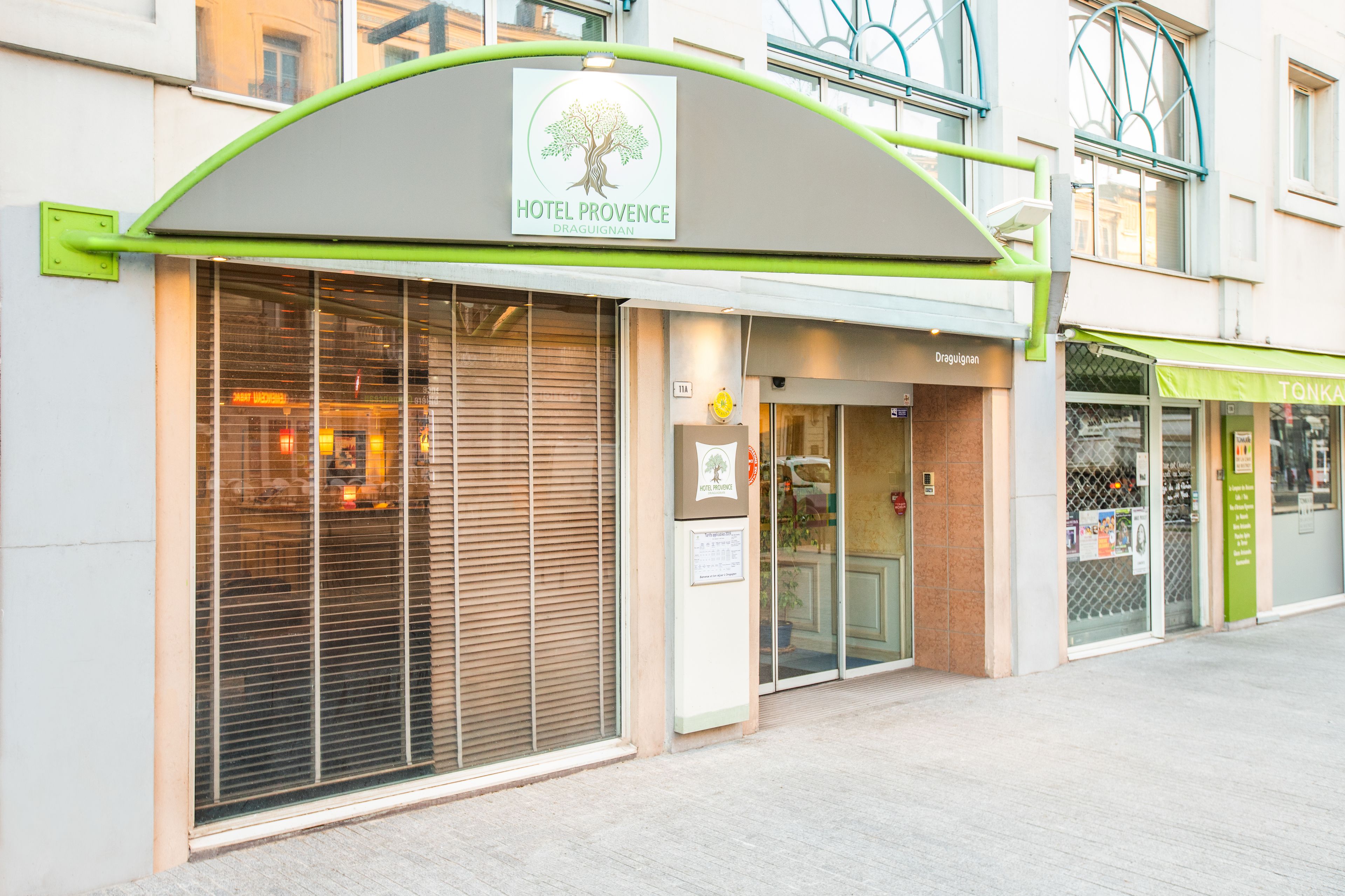 A hotel with a green awning and a sign that reads "HOTEL PROVENCE DRAGUIGNAN."