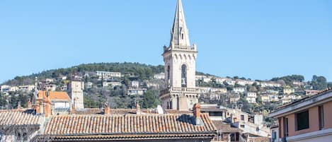 A historic town with a prominent church tower, terracotta-tiled rooftops, and a hillside of residential buildings.