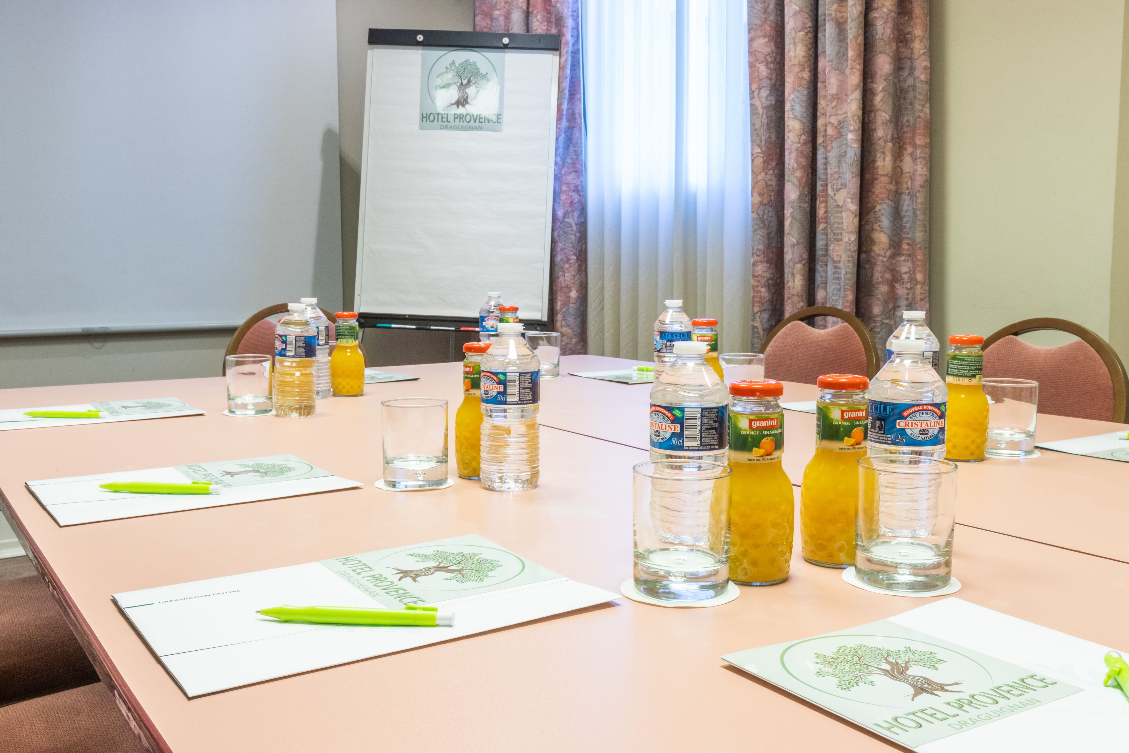 Un salón de conferencias con una mesa dispuesta para una reunión, con botellas de agua, vasos y tarjetas de identificación.