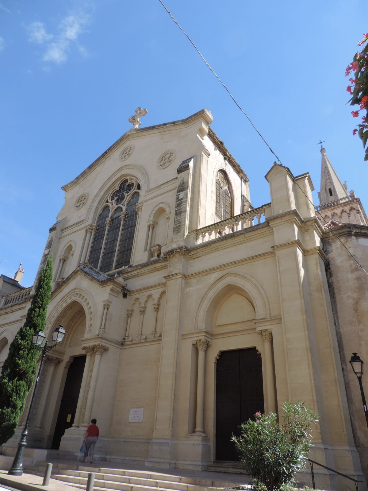 A historic building with a large arched entrance, a bell tower, and a cross on top.
