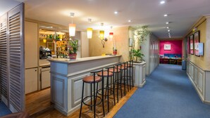 Zona de bar con taburetes, una barra y cocina al fondo.