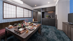 A modern dining area with a traditional Japanese-style sliding door, a kitchen with dark cabinetry, and a flat-screen TV on a wooden stand. - MIMARU Tokyo Ginza East (Tokyo)