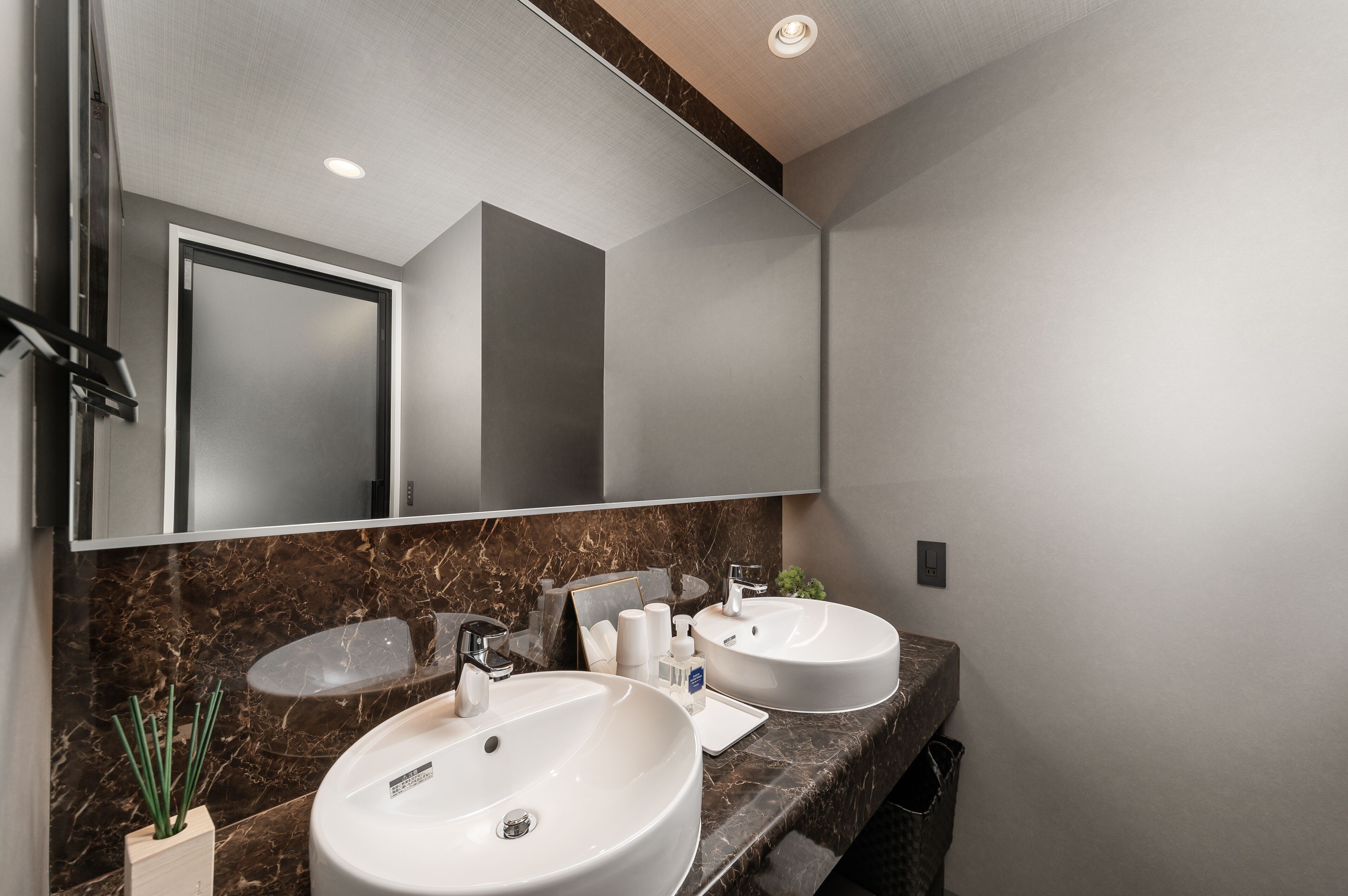 A modern bathroom with two sinks, a large mirror, and a marble countertop.