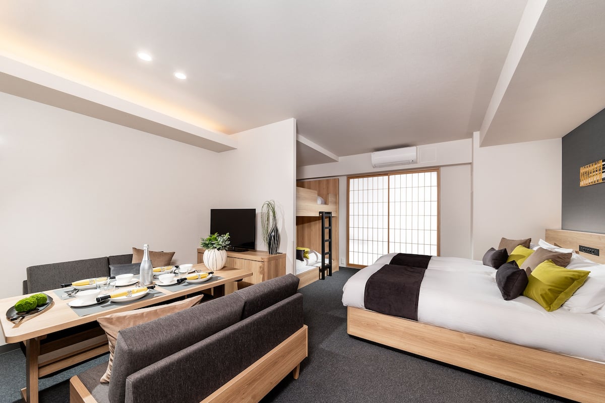 A modern hotel room with a bed, a desk, and a seating area.