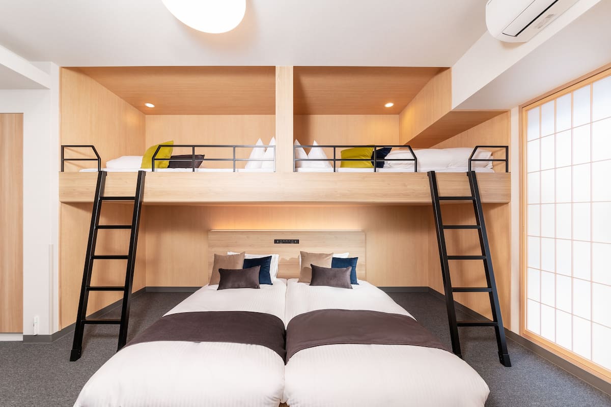 A bunk bed room with a wooden headboard, two ladders, and a large window with a view.