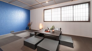 A traditional Japanese-style room with tatami flooring, a low table with cushions, a large window with shoji screens, and a blue accent wall. - MIMARU Tokyo Ginza East (Tokyo)