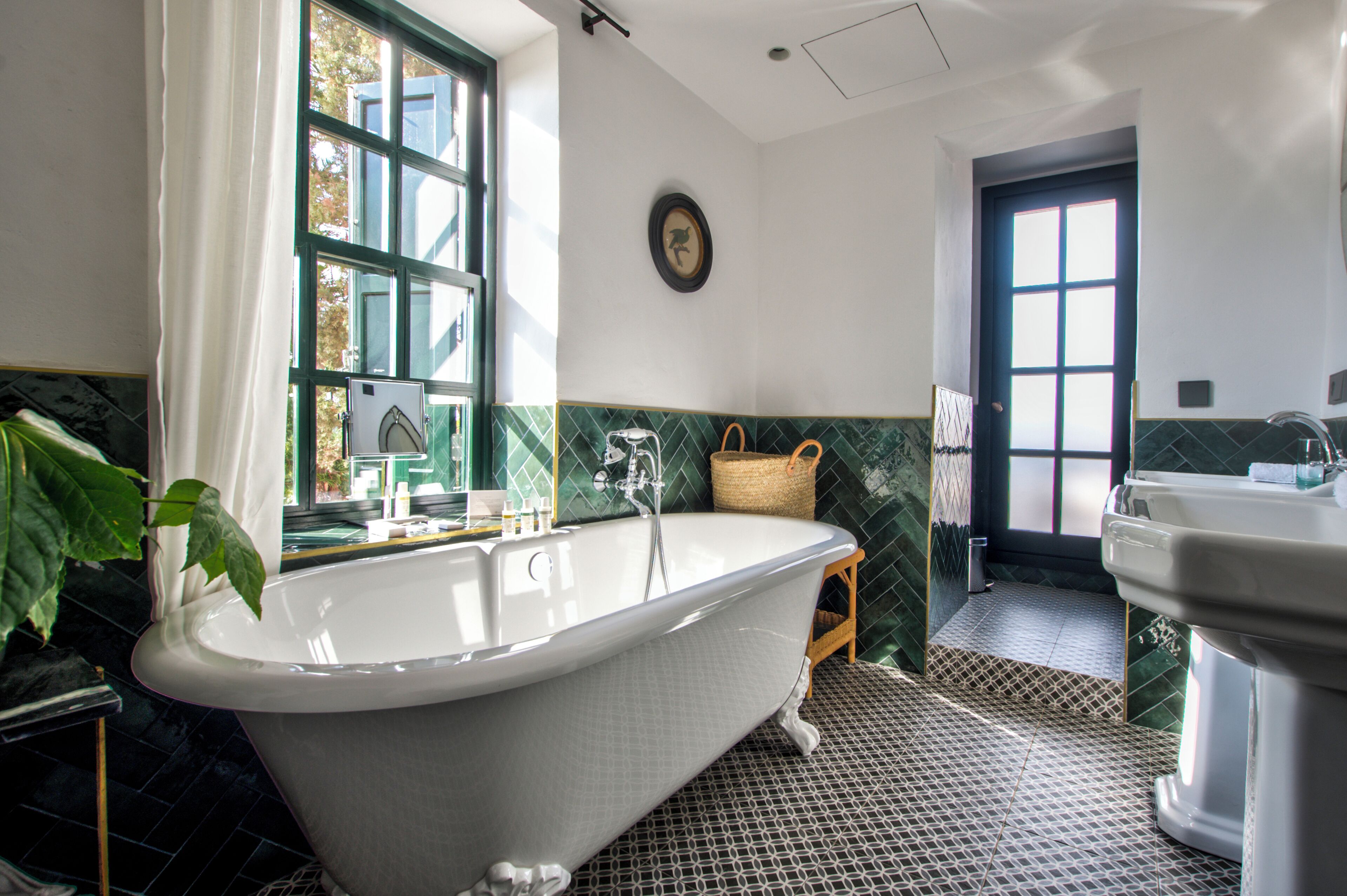 Ein Badezimmer mit einer freistehenden Badewanne, einem Waschbecken und einer Tür zu einem weiteren Raum.