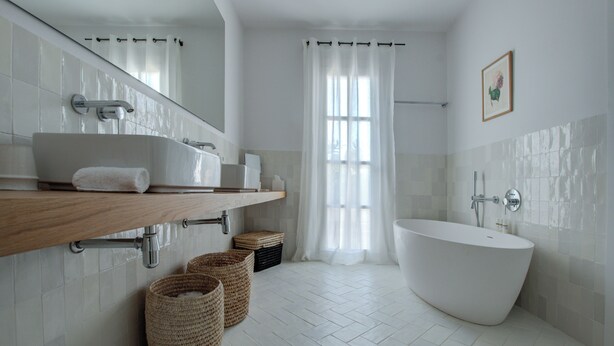 A modern bathroom with a freestanding bathtub, a vanity with a mirror, and a large window with sheer curtains. -  Santa Ponsa - Fontenille Collection (Alayor)