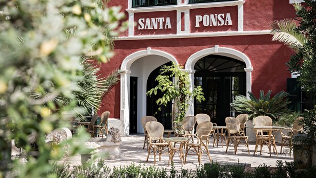 A red building with "SANTA PONSA" signage, outdoor wicker furniture, and a well-maintained garden. -  Santa Ponsa - Fontenille Collection (Alayor)