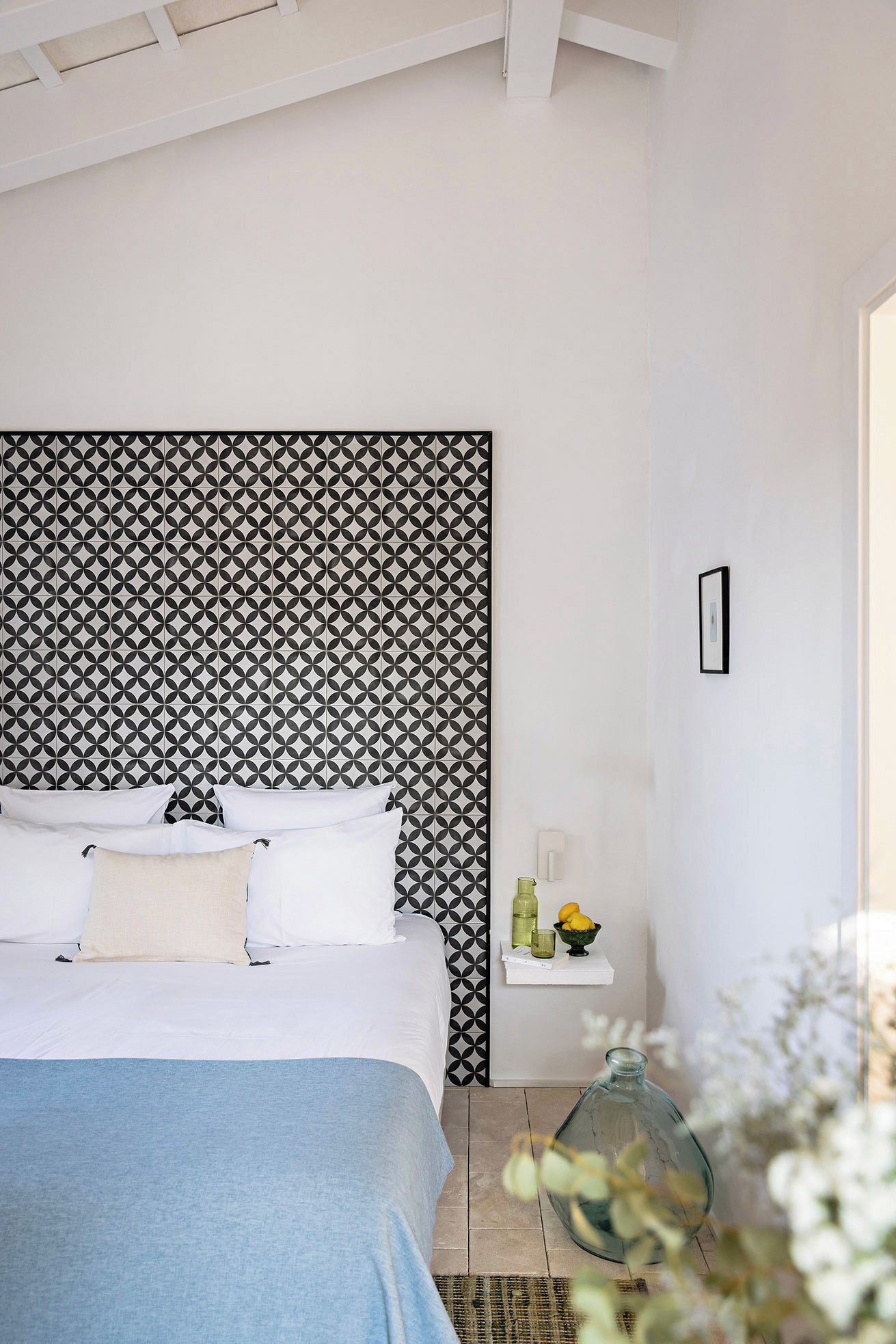 Un dormitorio con cama, mesita de noche y pared con diseño geométrico.