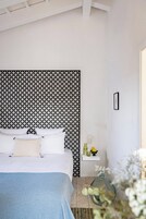 Un dormitorio con cama, mesita de noche y pared con diseño geométrico.