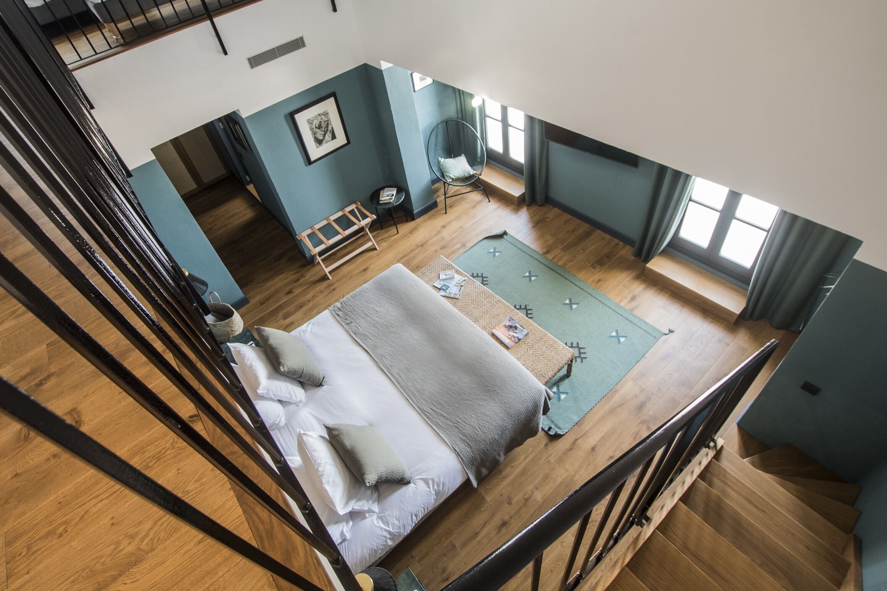 Una habitación con cama, una silla, una mesita y una ventana.