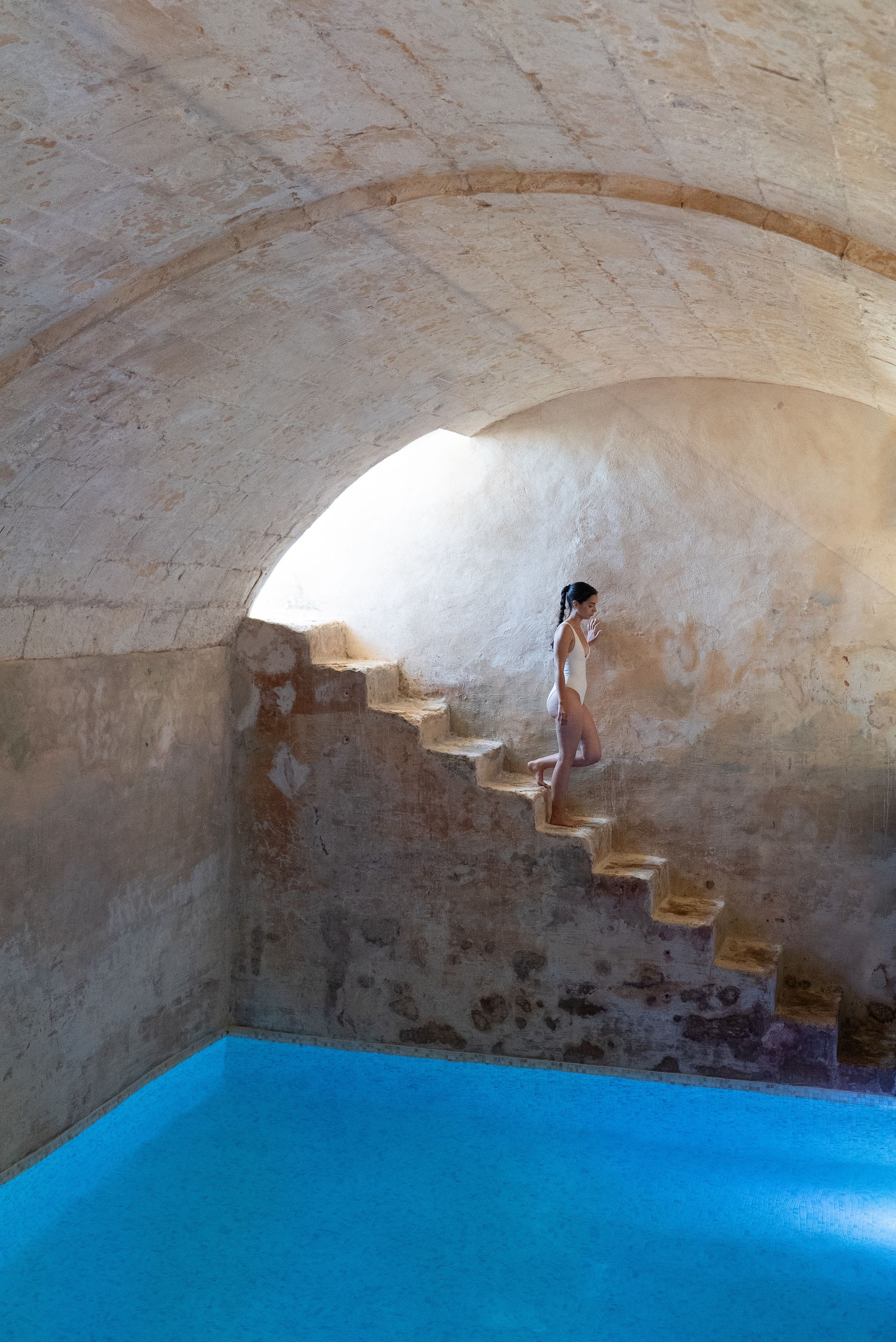 A person ascending a set of stone steps in a room with a blue floor and a sloped ceiling.