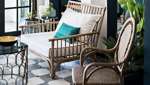 A room with a bed, wicker chairs, a round table, and large potted plants. -  Santa Ponsa - Fontenille Collection (Alayor)
