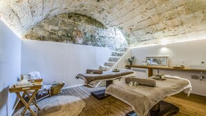 A spa room with wooden floors, a stone arch ceiling, and a massage table with towels. -  Santa Ponsa - Fontenille Collection (Alayor)