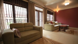 A living room with two sofas, a coffee table, and a patterned rug. - UM Apartments (Kigali)