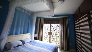 A bedroom with a bed, curtains, and a window with a decorative screen. - UM Apartments (Kigali)