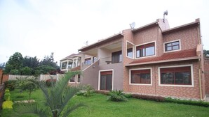 A multi-story residential building with balconies, satellite dishes, and a well-maintained garden. - UM Apartments (Kigali)
