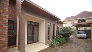 A residential house with a brick facade, a front door, and a garage. - UM Apartments (Kigali)