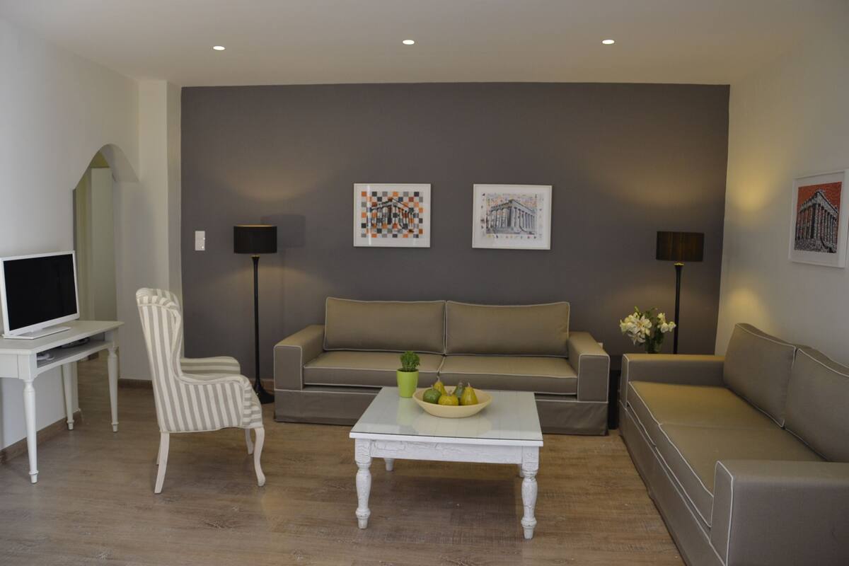 A living room with a sofa, armchairs, a coffee table, and artwork on the walls.