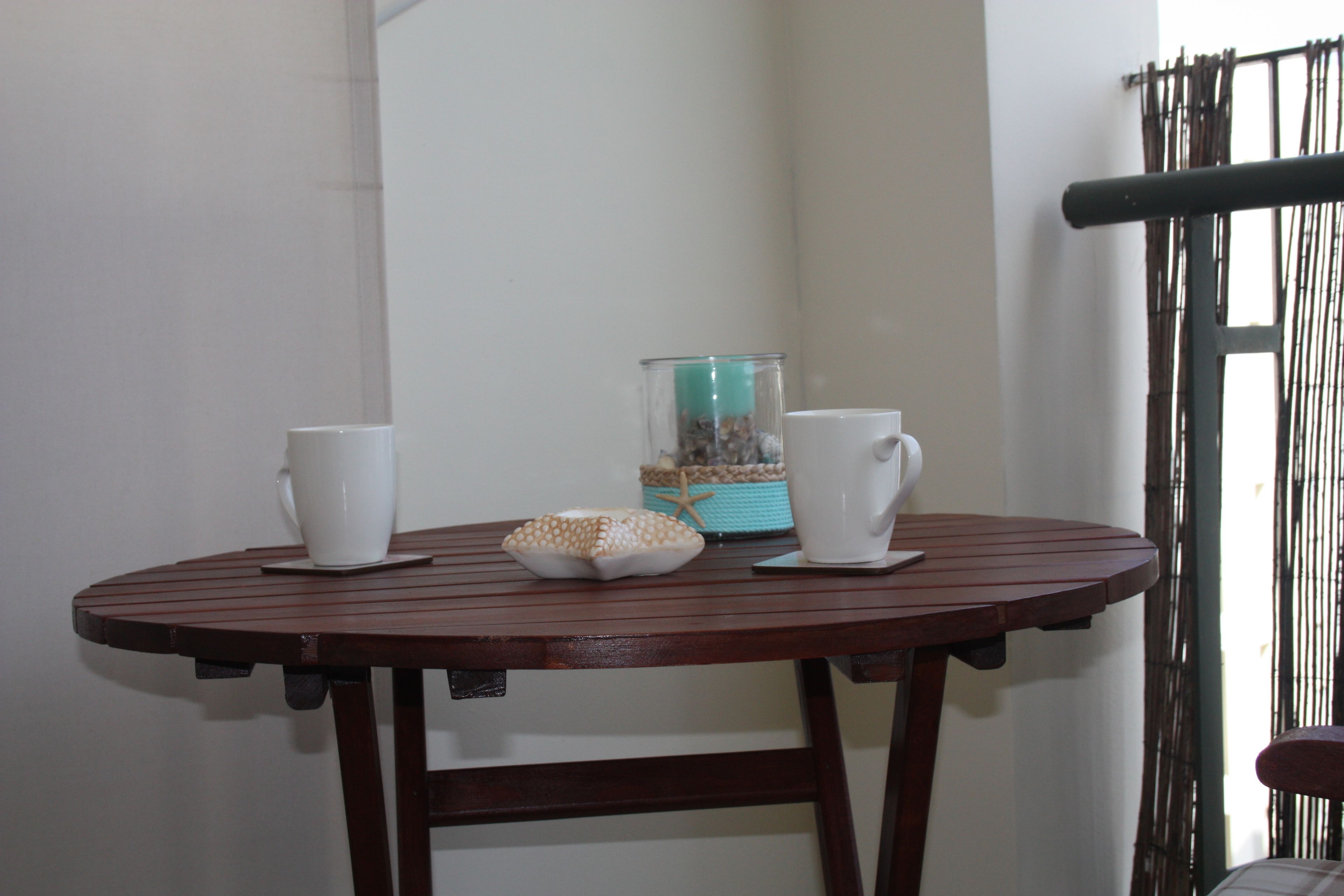 A round wooden table with two white cups and a decorative item.