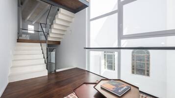 Um interior moderno com escada, janelas amplas e uma pequena mesa com um livro.