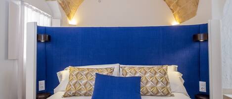 A bedroom with a white bed, blue headboard, and patterned pillows.