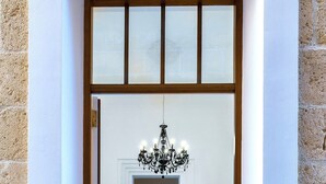 A hotel entrance with a tiled floor, a chandelier, and a seating area with chairs and a table.