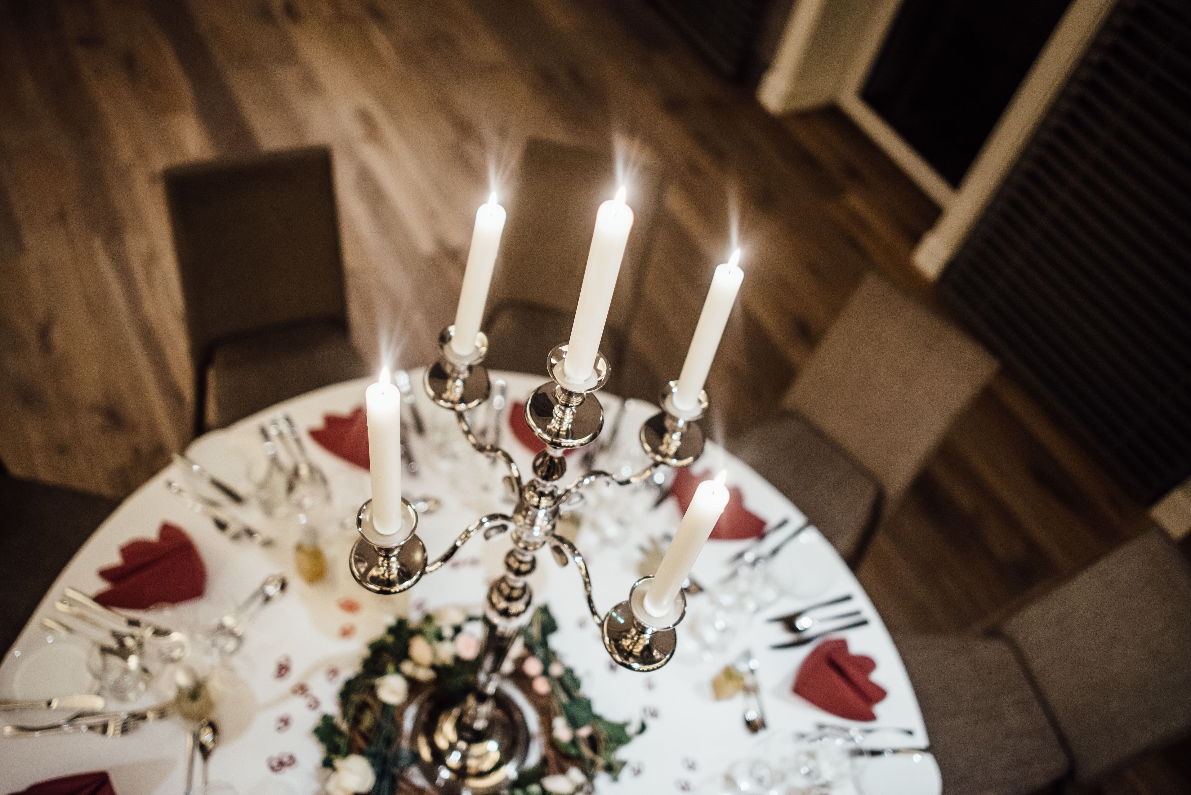 Una mesa vestida con un mantel blanco, un centro de mesa floral y un candelabro con velas encendidas.