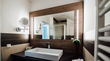 A modern bathroom with a large mirror, a white sink, and a wooden accent wall.