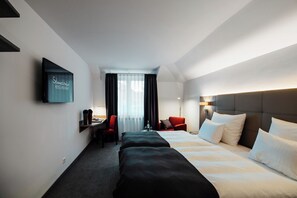 A hotel room with a large bed, a desk with a chair, a TV mounted on the wall, and a window with curtains. - Hotel und Restaurant Schmachtendorf (Oberhausen)
