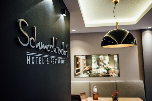 A hotel sign with 'Schmohardt HOTEL & RESTAURANT' and a dining area with a table and chairs. - Hotel und Restaurant Schmachtendorf (Oberhausen)