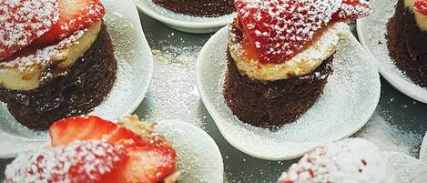 A display of desserts, each topped with strawberries and powdered sugar.