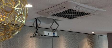 A ceiling with a geometric light fixture, a projector, and a vent.