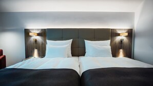 Un lit double avec une tête de lit en bois, deux lampes de chevet et une chaise rouge.