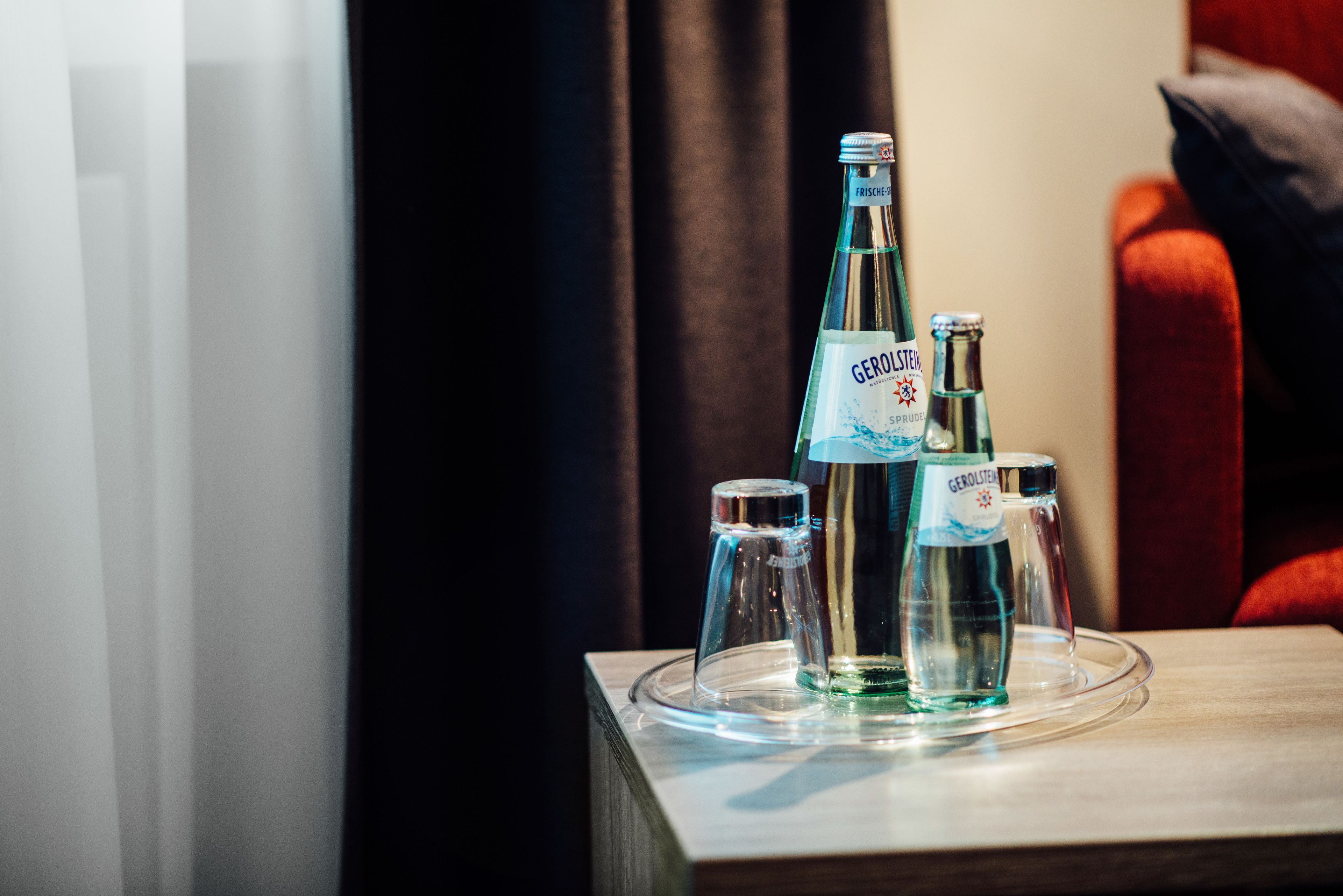 A table with three Gerolsteiner water bottles and two glass carafes on a tray.