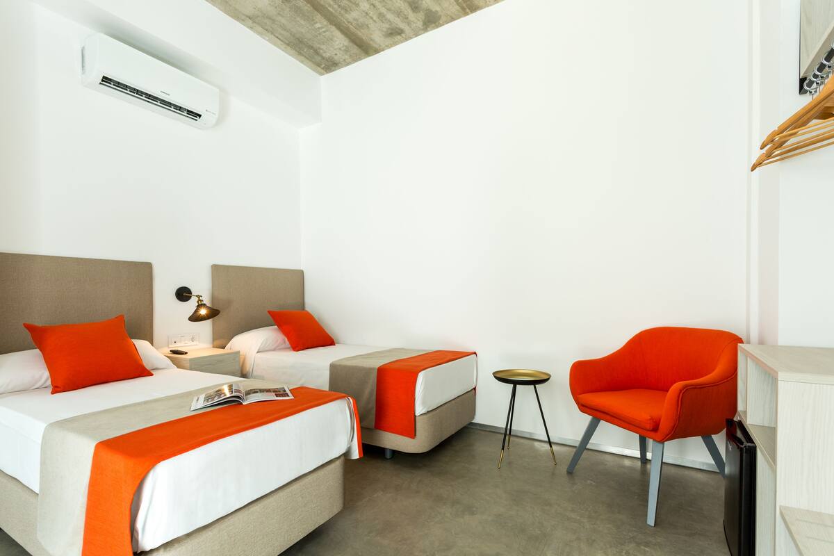 Een hotelkamer met twee bedden, een tafeltje, een stoel en een inbouwkast.