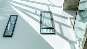 Un interno moderno con lucernari e ampie finestre che lasciano entrare molta luce naturale.