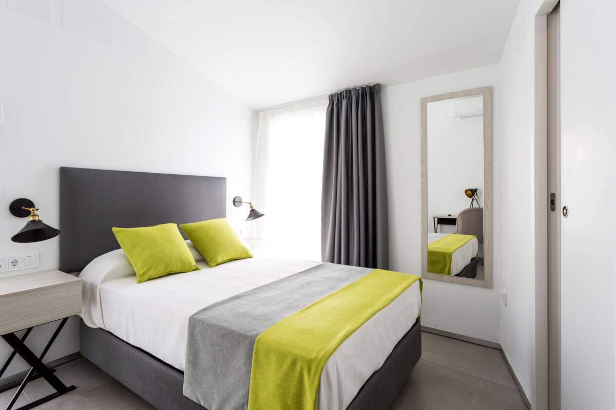 Een moderne hotelkamer met een groot bed, een bureau en een spiegel.