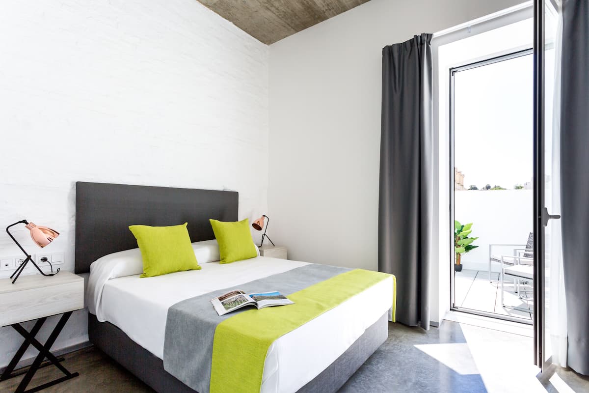 Een hotelkamer met een bed, nachtkastje, leeslamp en uitzicht.