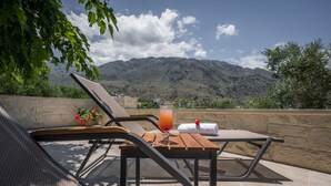 A terrace with a table, chairs, and a drink, overlooking a mountainous landscape. - Pagonas Traditional House (Apokoronas)