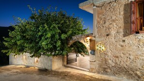 A stone building with an arched entrance, a tree in front, and a gate. - Pagonas Traditional House (Apokoronas)