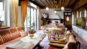 A cozy interior with a sofa, dining table, and chairs, a fireplace, and a television.