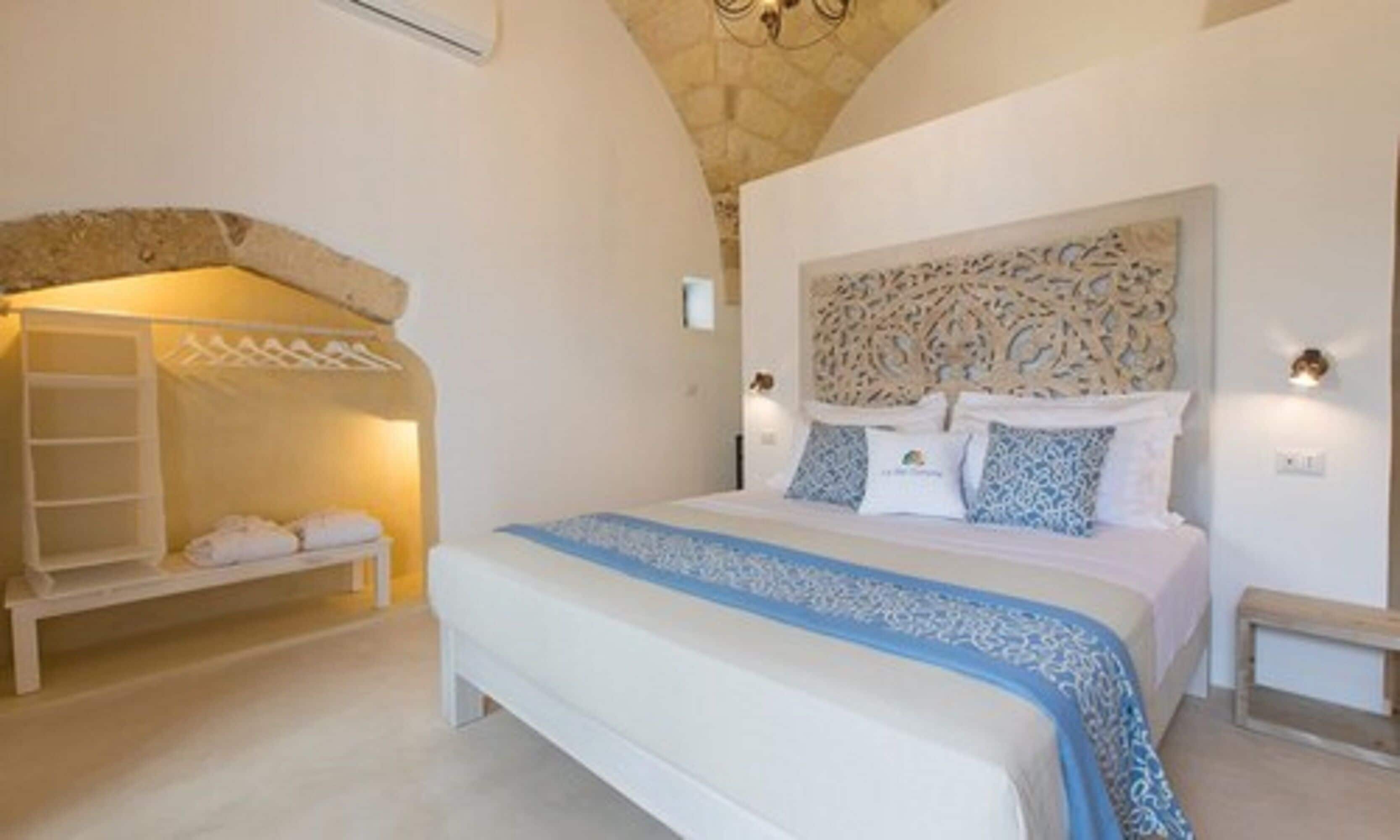 Ein Schlafzimmer mit einem großen Bett, einer Bank, einem Wandregal und einem dekorativen Kopfteil.