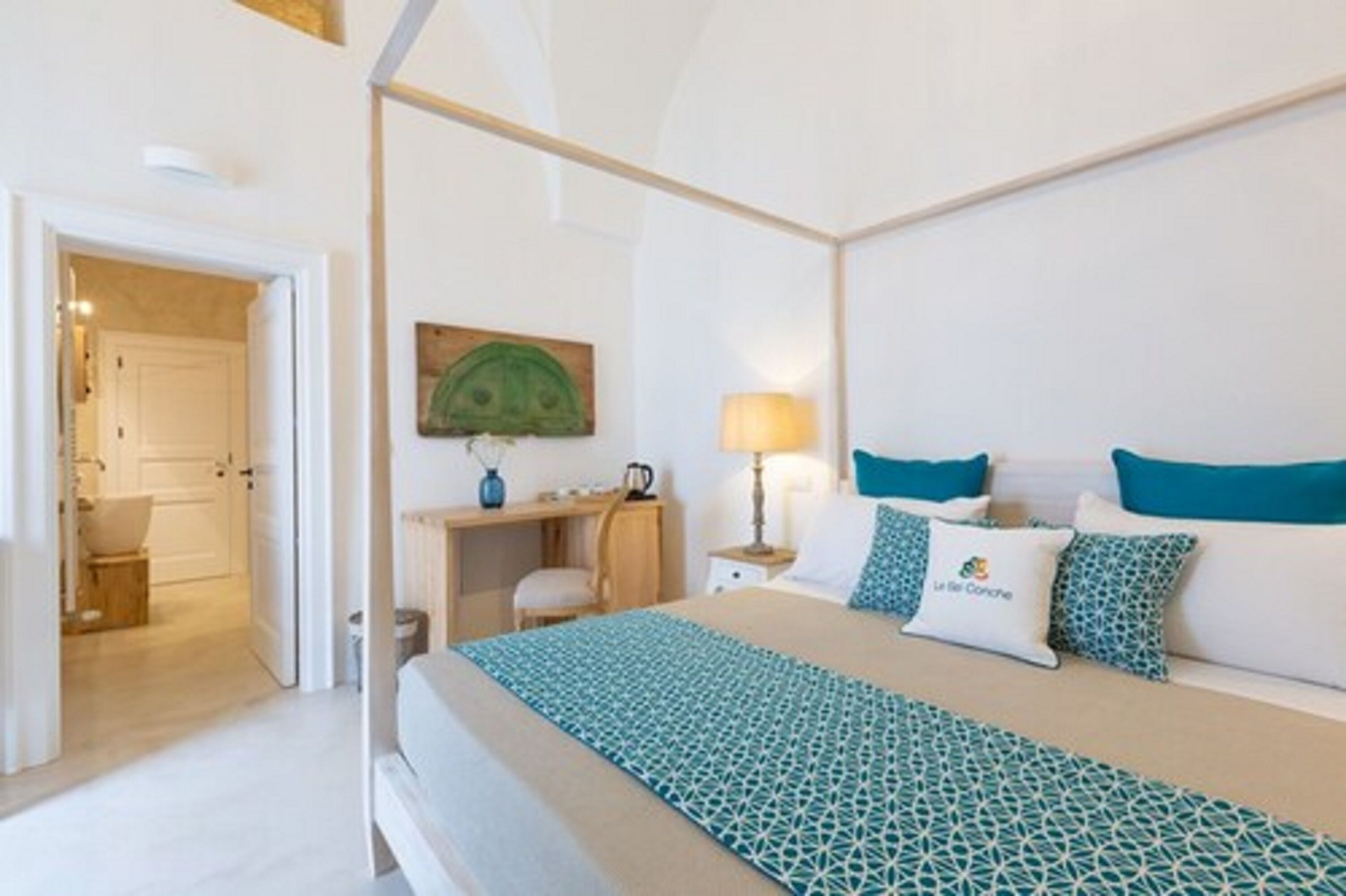 Ein Hotelzimmer mit Bett, Schreibtisch und Stuhl. An der Wand hängt ein Bild, auf dem Schreibtisch steht eine Lampe.