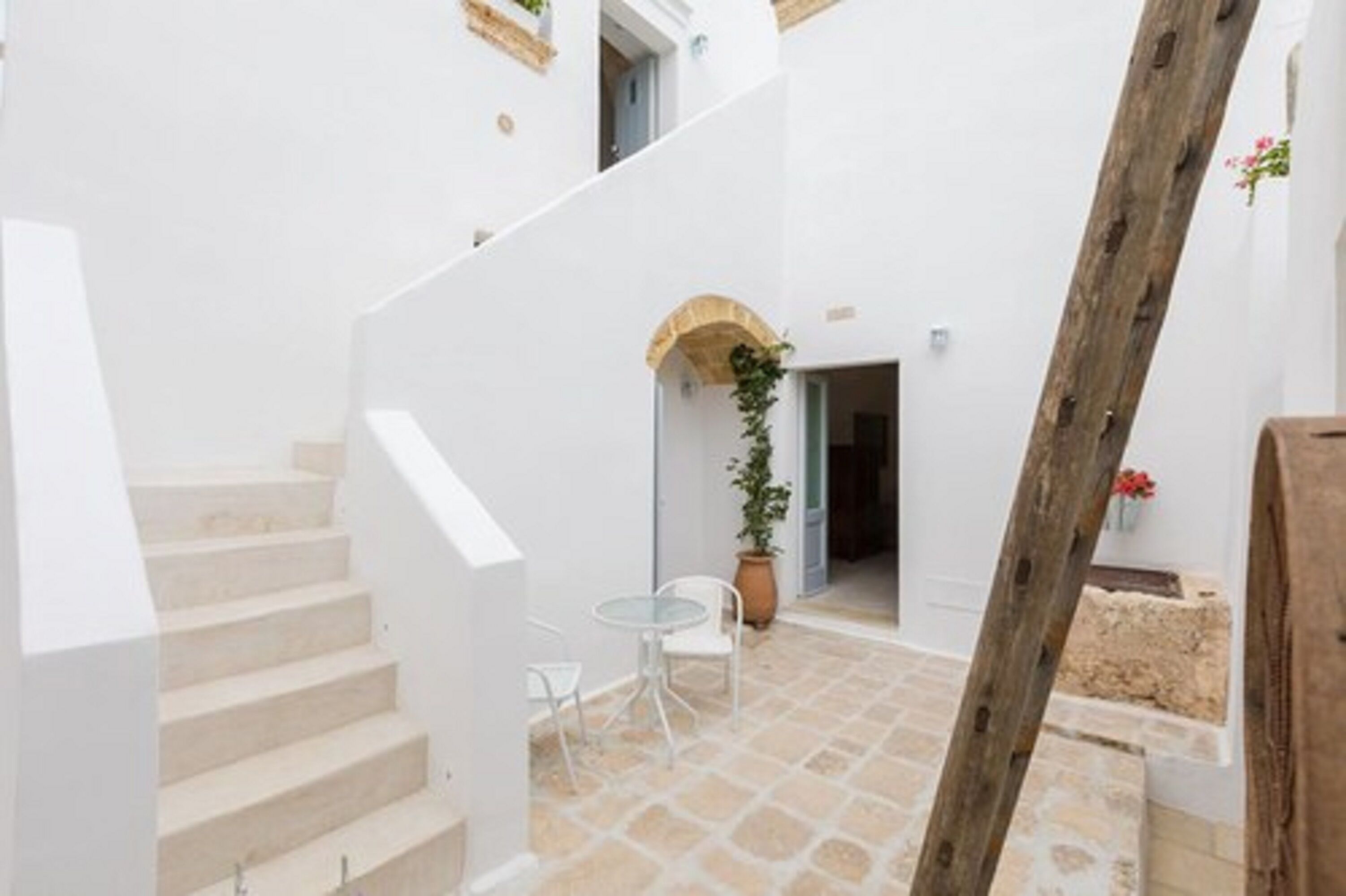 A white interior with a staircase leading to a small patio area with a table and chairs.