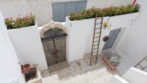 A narrow courtyard with a stone floor, a wooden door, and a ladder leaning against a wall. - Le Sei Conche Relais & Spa (Ugento)