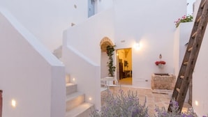 A white-walled building with a staircase leading to an interior room, a wooden ladder, and a planter with purple flowers. - Le Sei Conche Relais & Spa (Ugento)