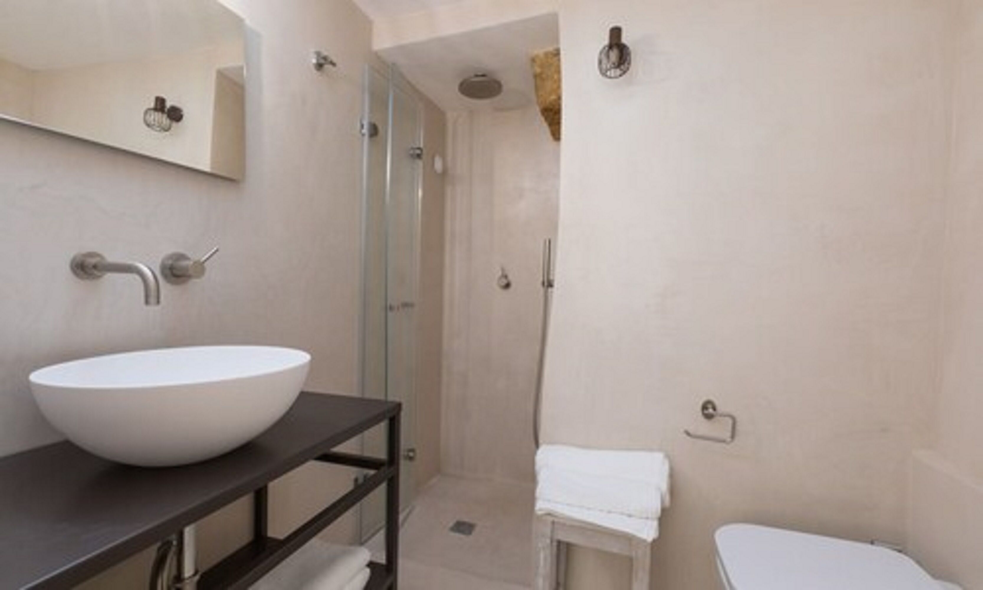 A modern bathroom with a large white sink, a glass shower enclosure, and a white toilet.